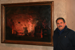 Vittorio Ferrarini e un dipinto di Josef Štolovský (“Interno di fonderia”, 1920-1930, olio su tela), la prima opera del Realismo Socialista da lui trovata in un “antik” praghese / Vittorio Ferrarini and a painting by Josef Štolovský (“Interior of the foundry”, 1920-1930, oil on canvas), the first work of Socialist Realism that he found in a Prague’s “antik”